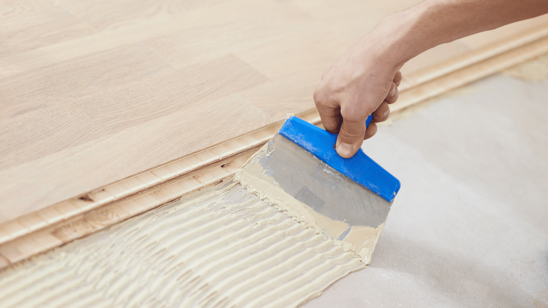 personne qui pose de la colle à parquet
